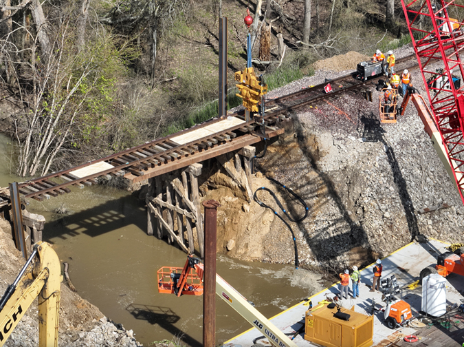 Crews work to replace the washed-out culvert with a bridge.